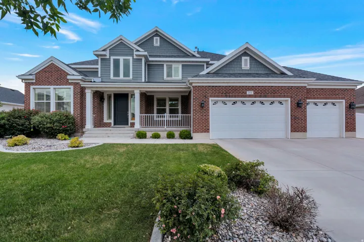 Two-story residence featuring brick and siding facade, a covered front porch, and a multi-car garage