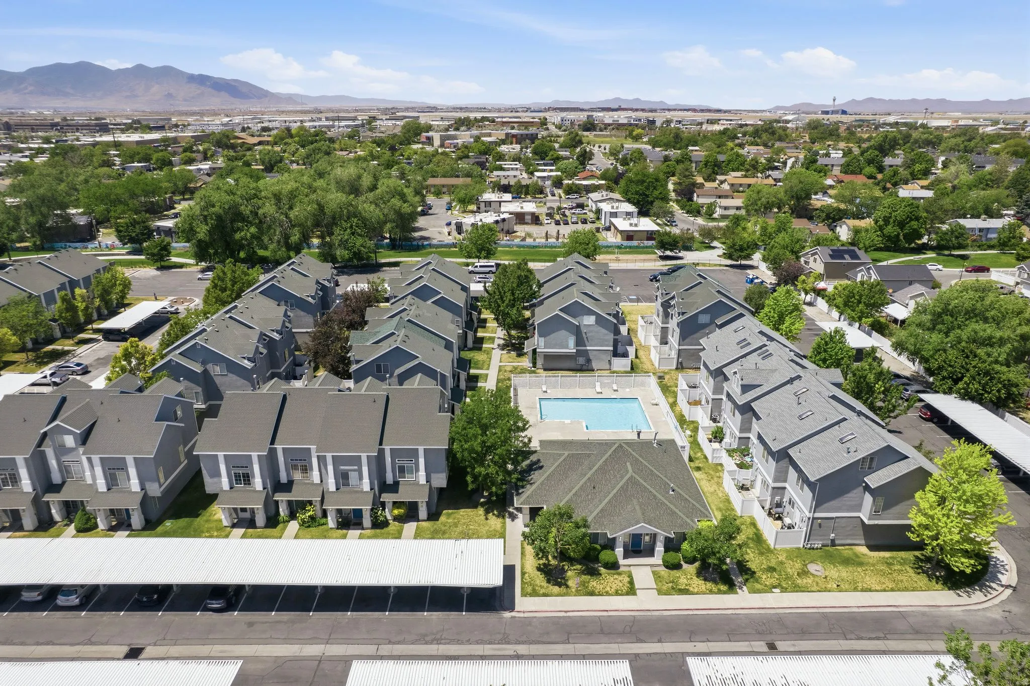Aerial perspective showcasing a multi-building property featuring a central swimming pool and multiple carports