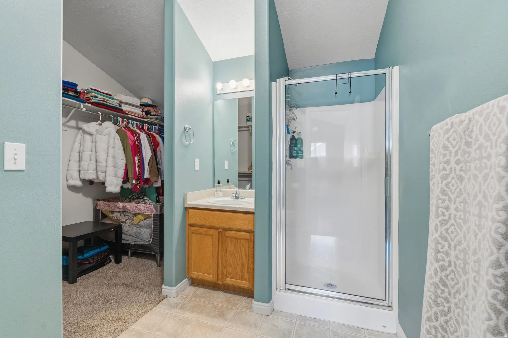 Bathroom with single vanity featuring a wood-finish cabinet and a shower enclosure with a glass door