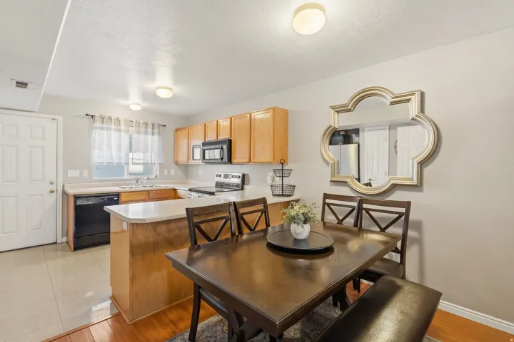 Open-concept kitchen and dining area featuring light wood cabinetry and black appliances