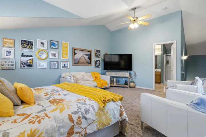 Spacious room featuring vaulted ceilings, a ceiling fan, and light blue wall tones