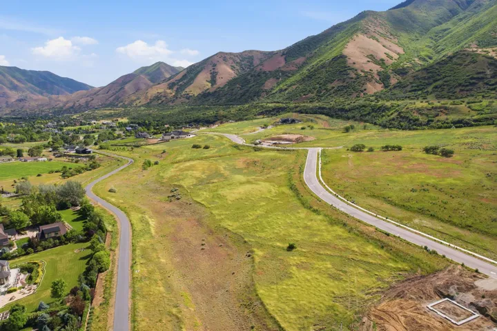 Expansive mountain landscape featuring rolling green hills and paved roadways