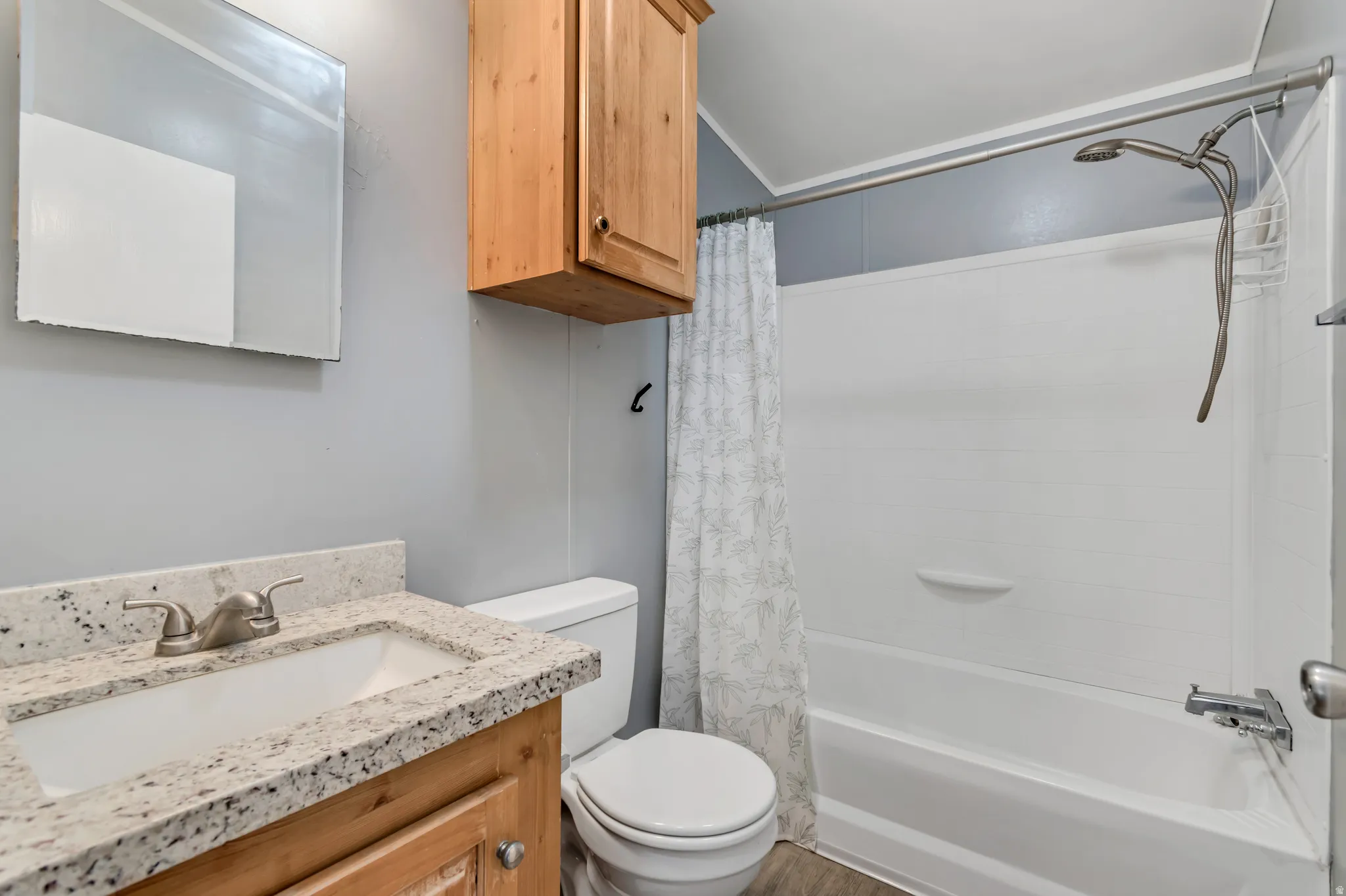 Bathroom featuring a light wood-finish vanity with a granite-style countertop, undermount sink, and a brushed nickel faucet