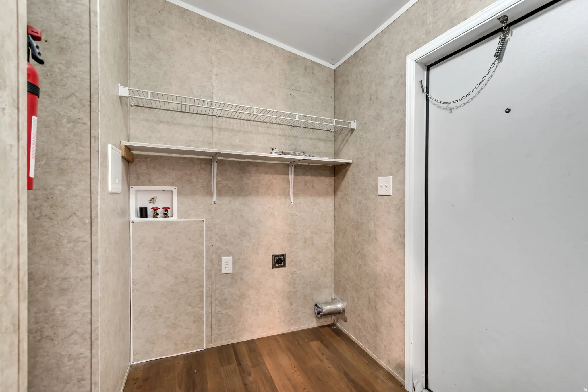 Dedicated laundry area featuring wood-finish flooring, patterned wall panels, and white wire shelving