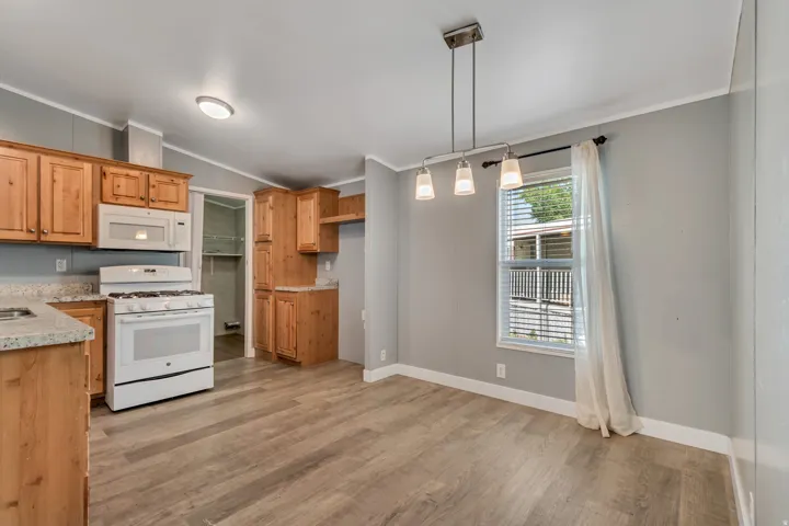 Open-concept kitchen and dining area featuring wood-finish flooring, light grey wall paint, and natural wood cabinetry