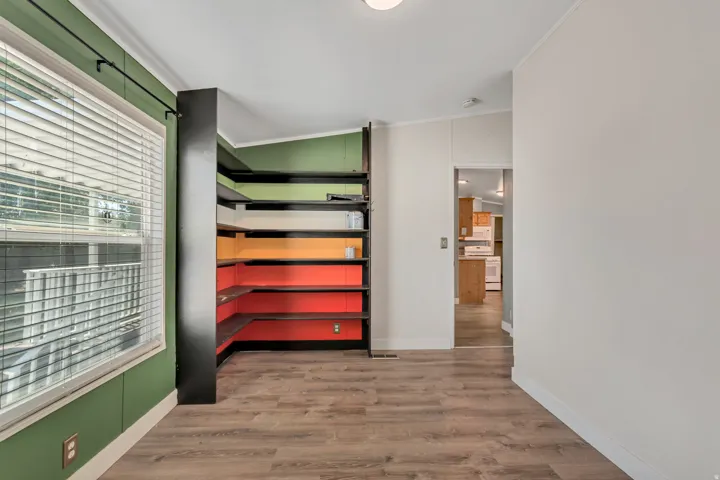 Room with wood-finish flooring and a corner built-in shelving unit