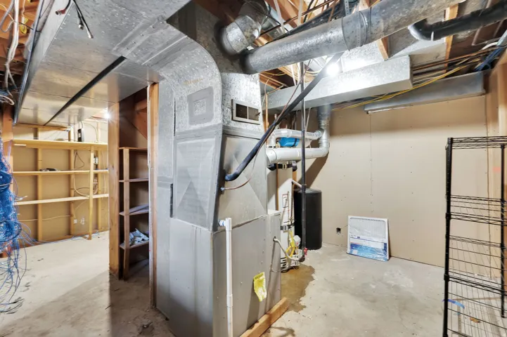Utility room featuring exposed ductwork, a water heater, and unfinished walls