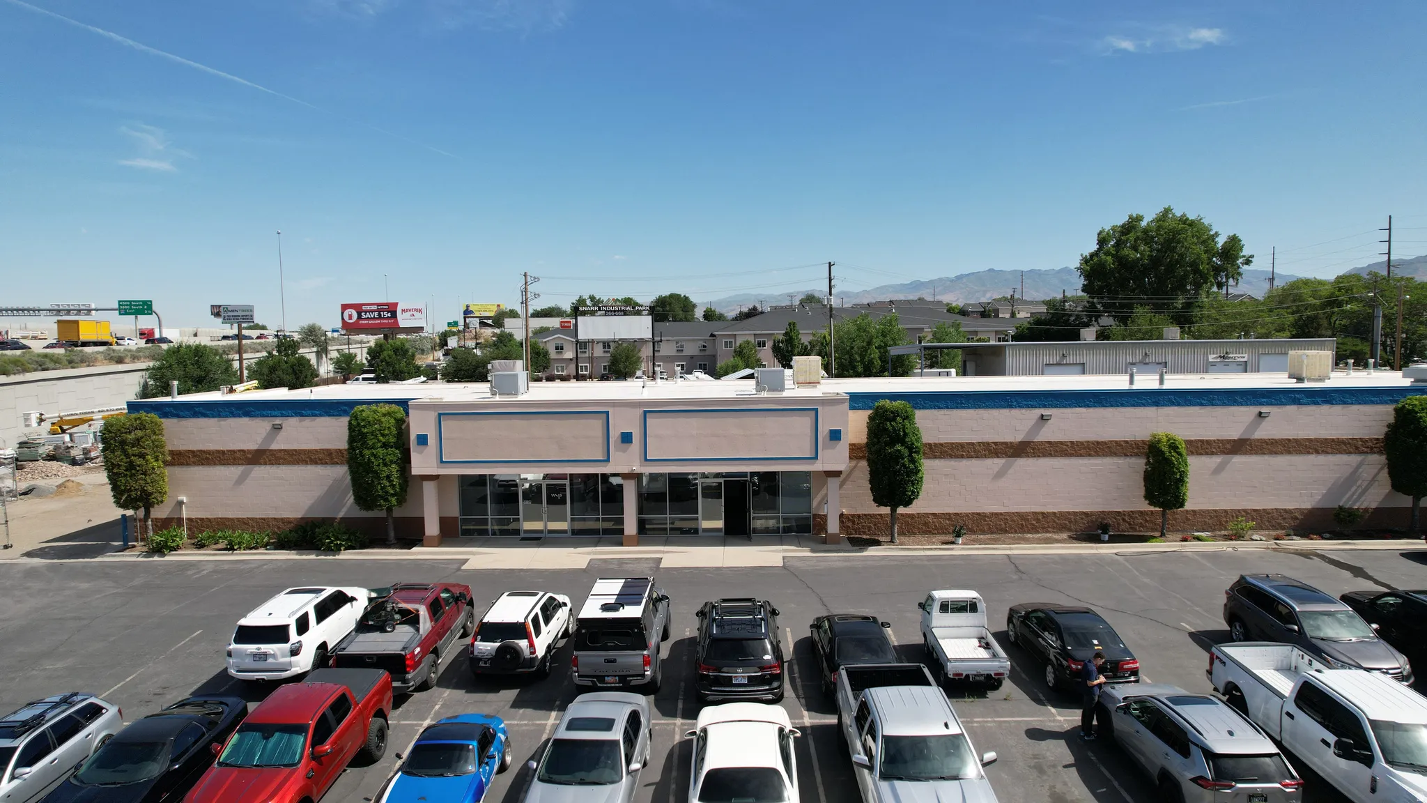 Commercial building with a spacious paved parking lot, featuring a light-colored stucco exterior with contrasting blue trim and multiple large storefront windows