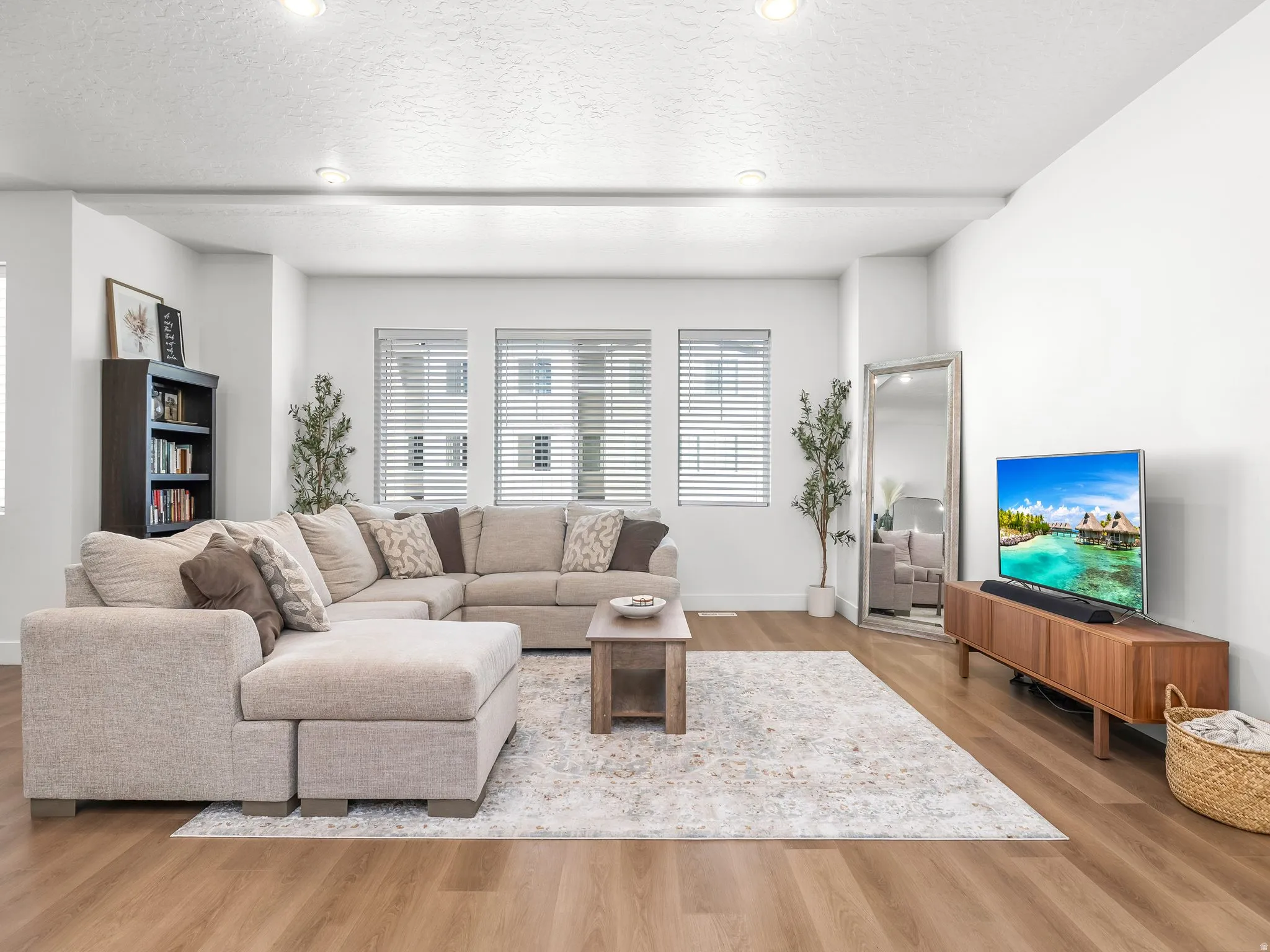 Bright living area featuring wood-finish flooring, recessed lighting, and white horizontal window blinds