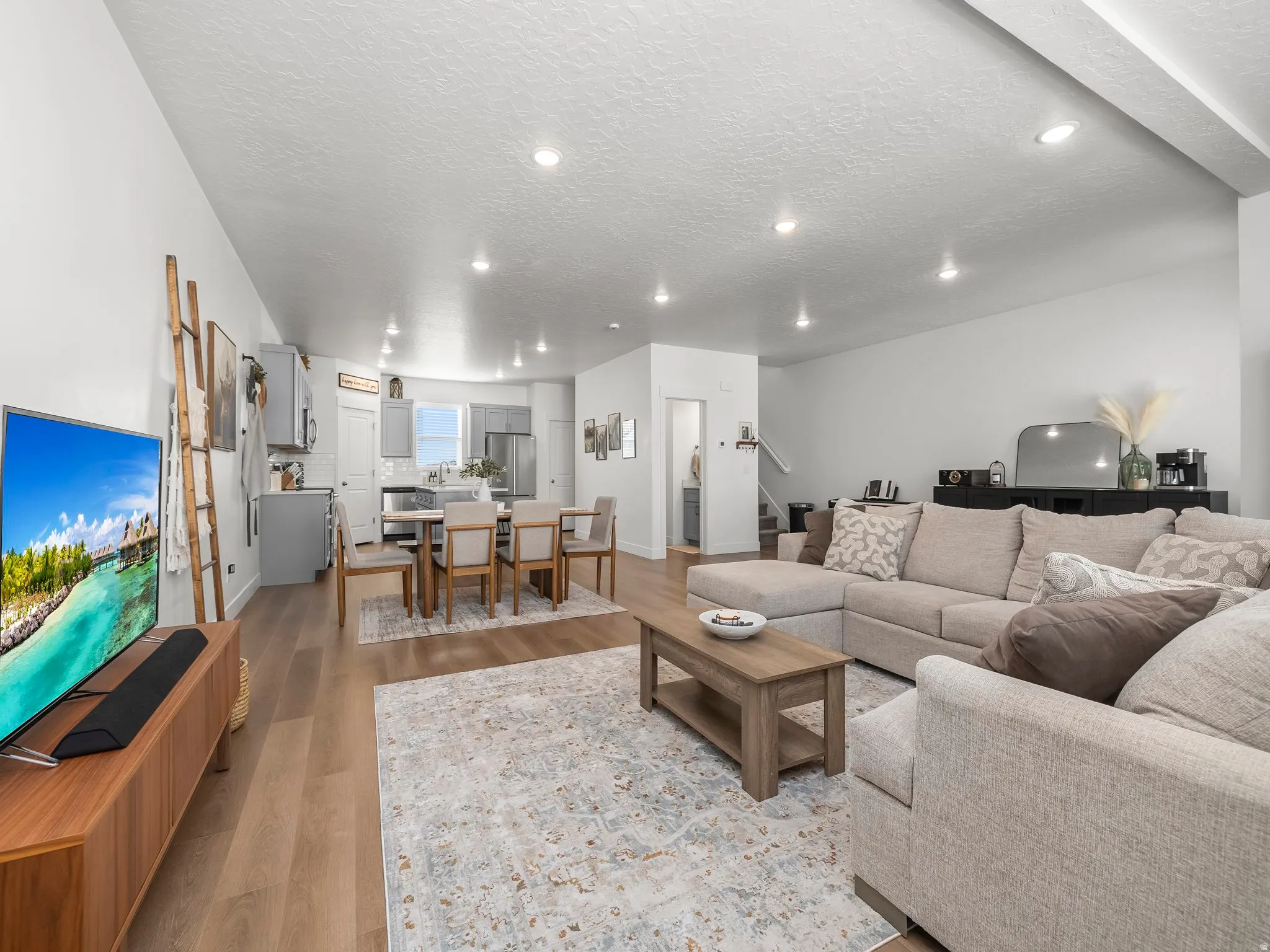 Open-concept living area featuring wood-finish flooring, recessed lighting, and a dining space with a contemporary chandelier