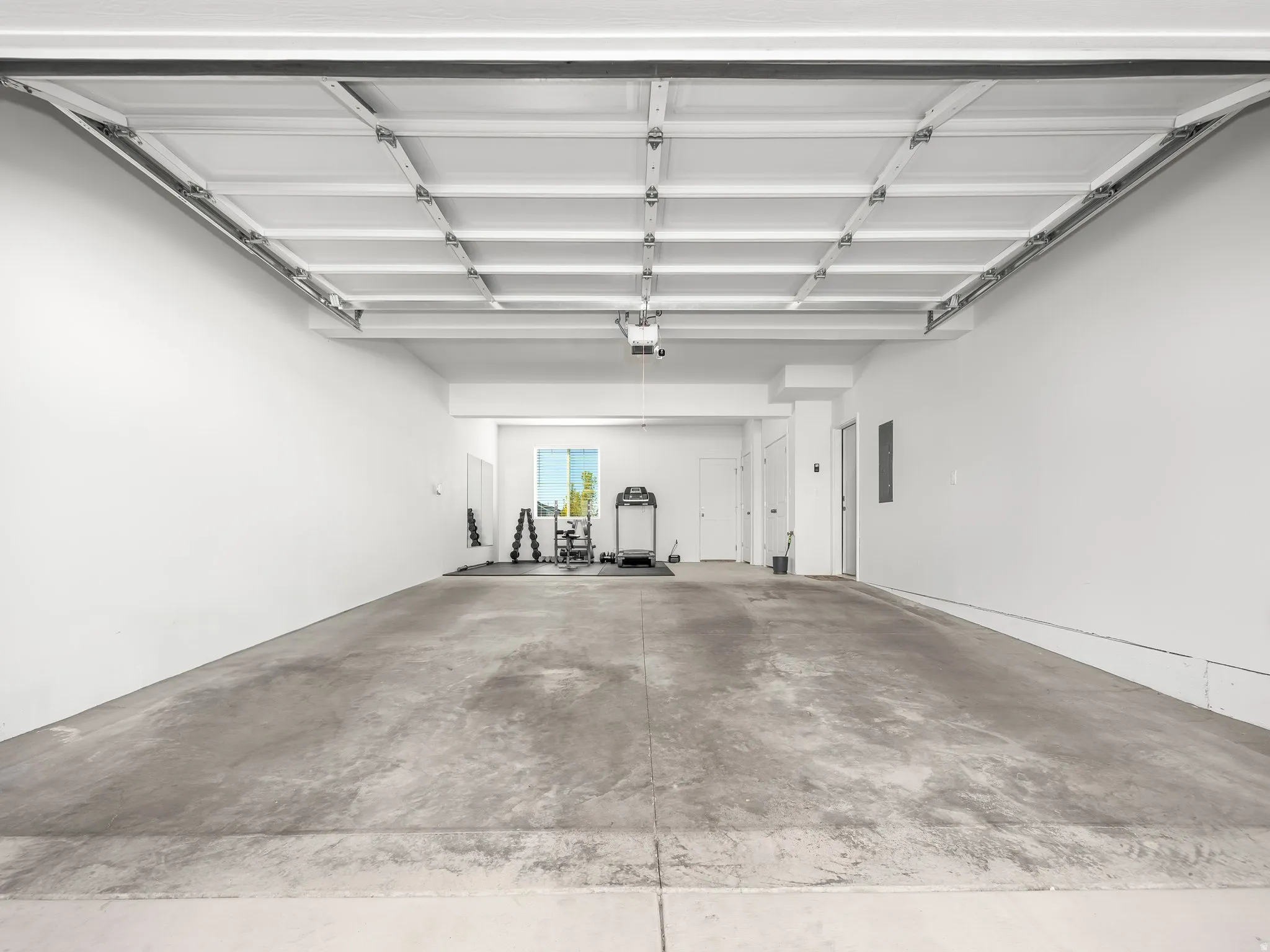 Spacious garage featuring a concrete floor, white painted walls, and an overhead garage door mechanism