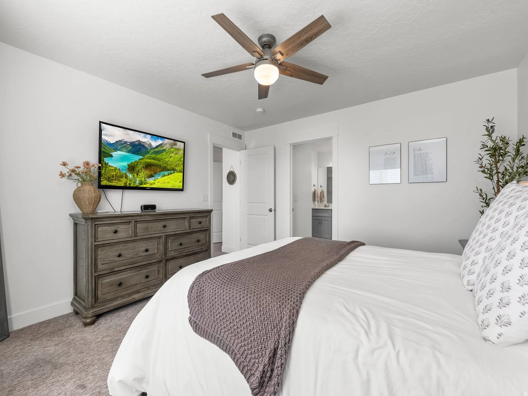 Spacious room featuring neutral carpeting, a ceiling fan with wood-finish blades, and white walls