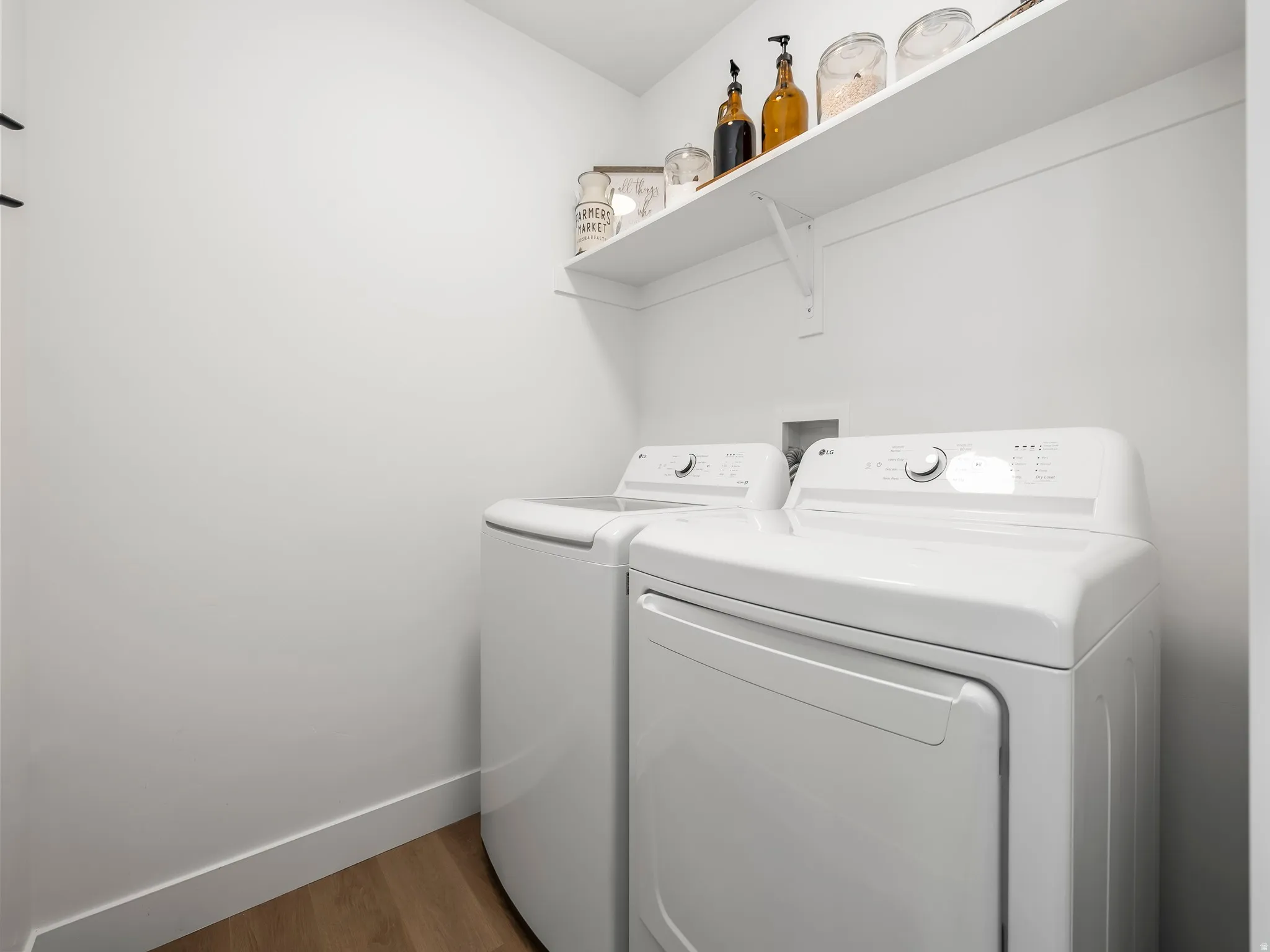 Laundry area featuring a built-in wall shelf, light wood-finish flooring, and white walls