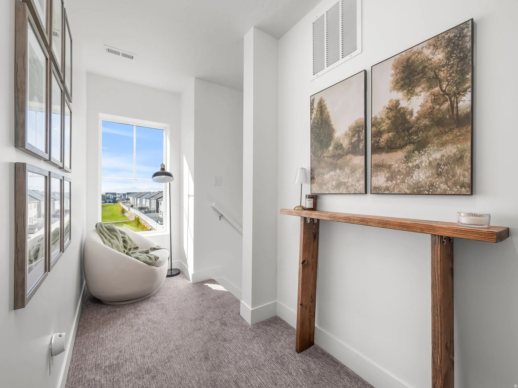 Carpeted hallway featuring a large window, white trim, and a rustic wood console table