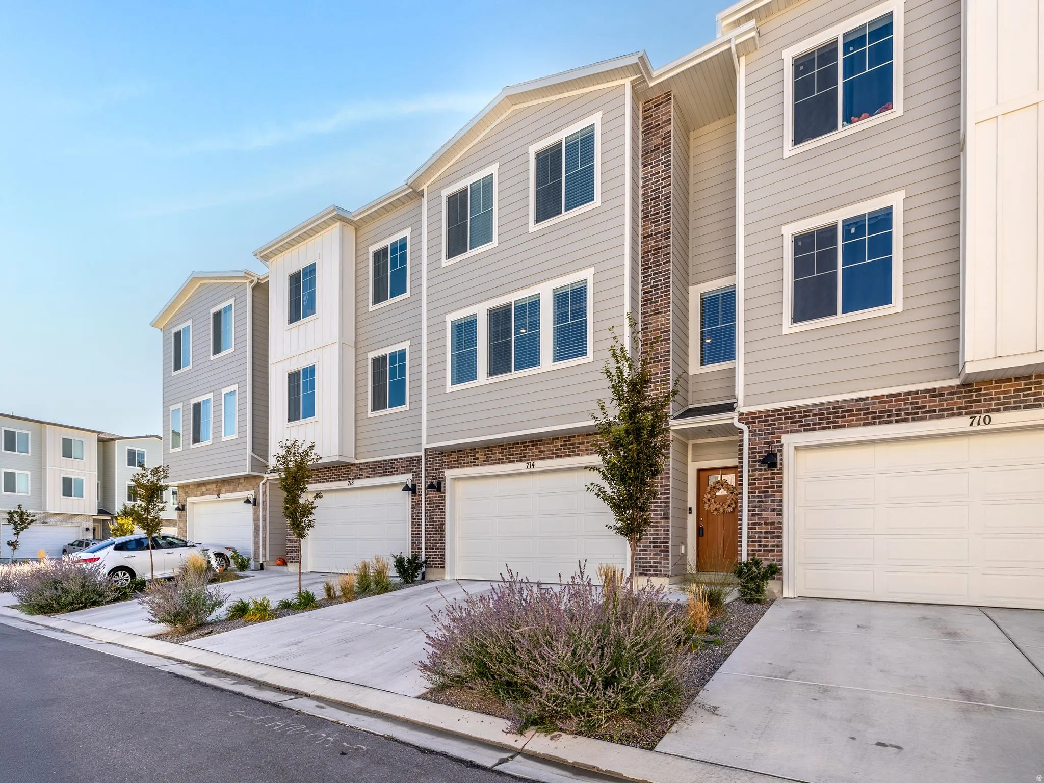 Contemporary multi-level townhome featuring a mixed-material exterior with light gray siding and brick accents