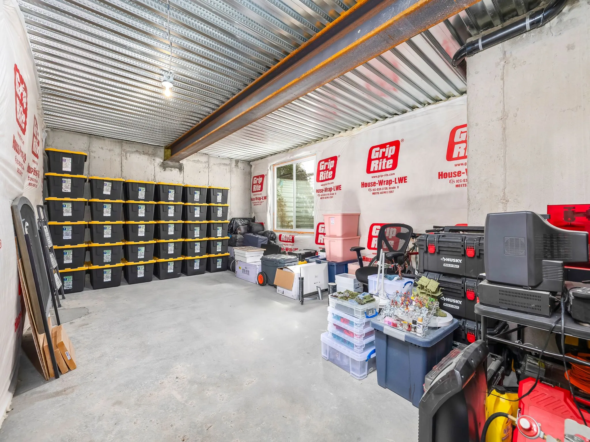 Unfinished basement space featuring concrete walls, a concrete floor, and exposed metal ceiling beams
