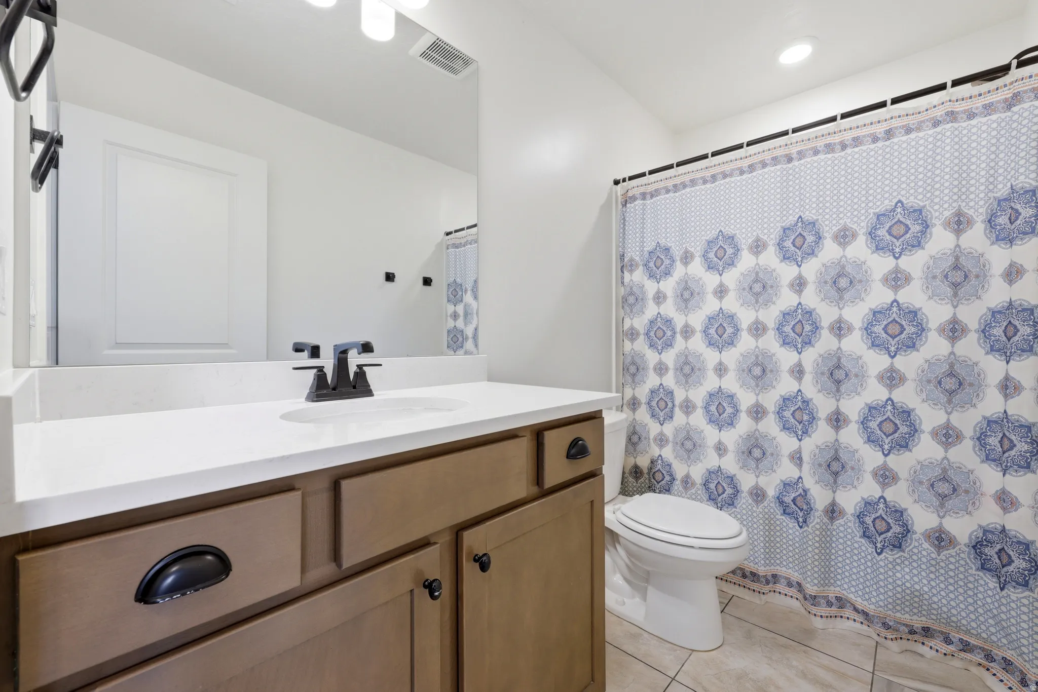 Bathroom vanity with a white countertop, undermount sink, and matte black faucet
