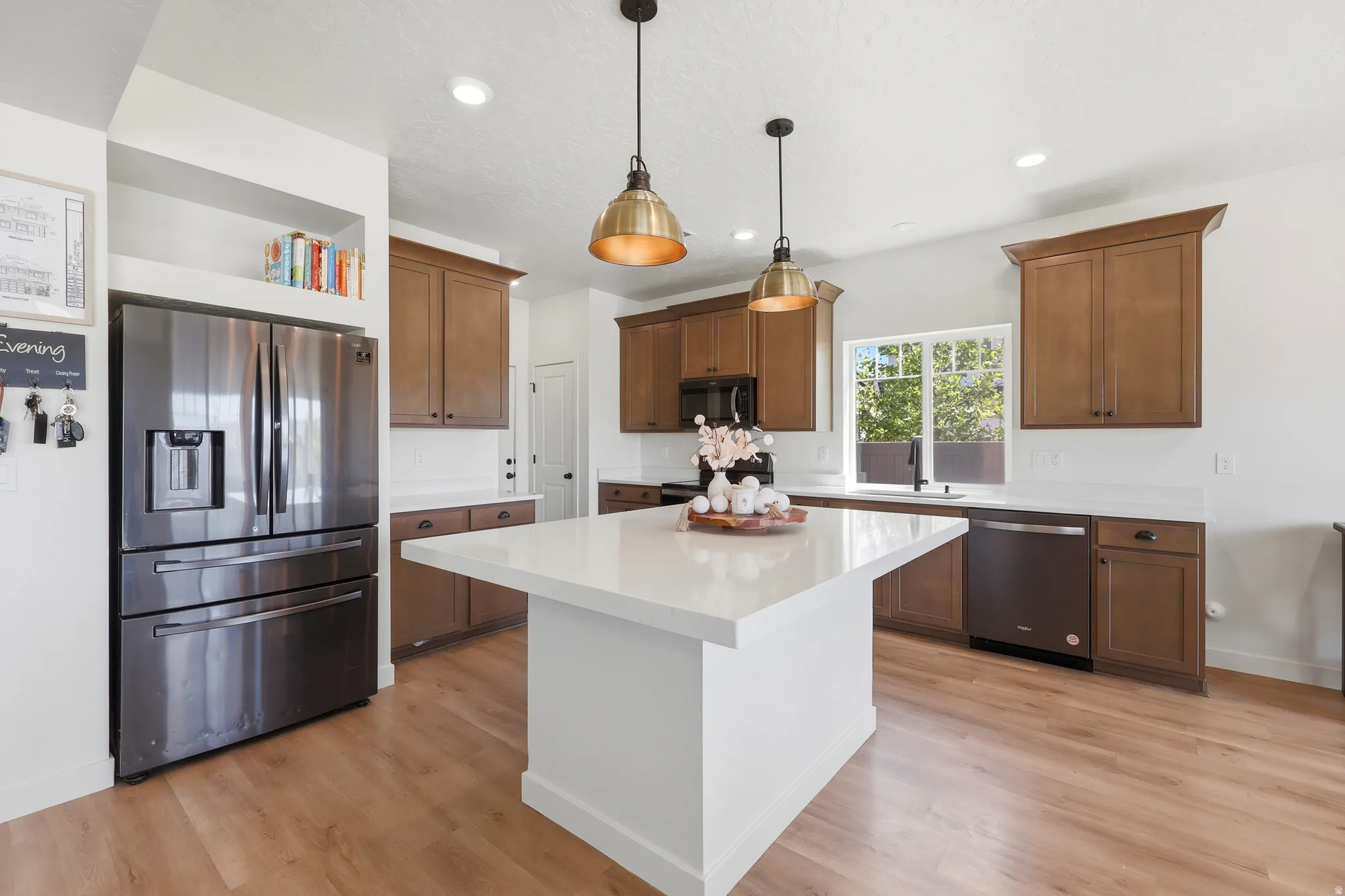 Kitchen featuring a central island with a white countertop, wood-finish flooring, recessed lighting, and two pendant lights