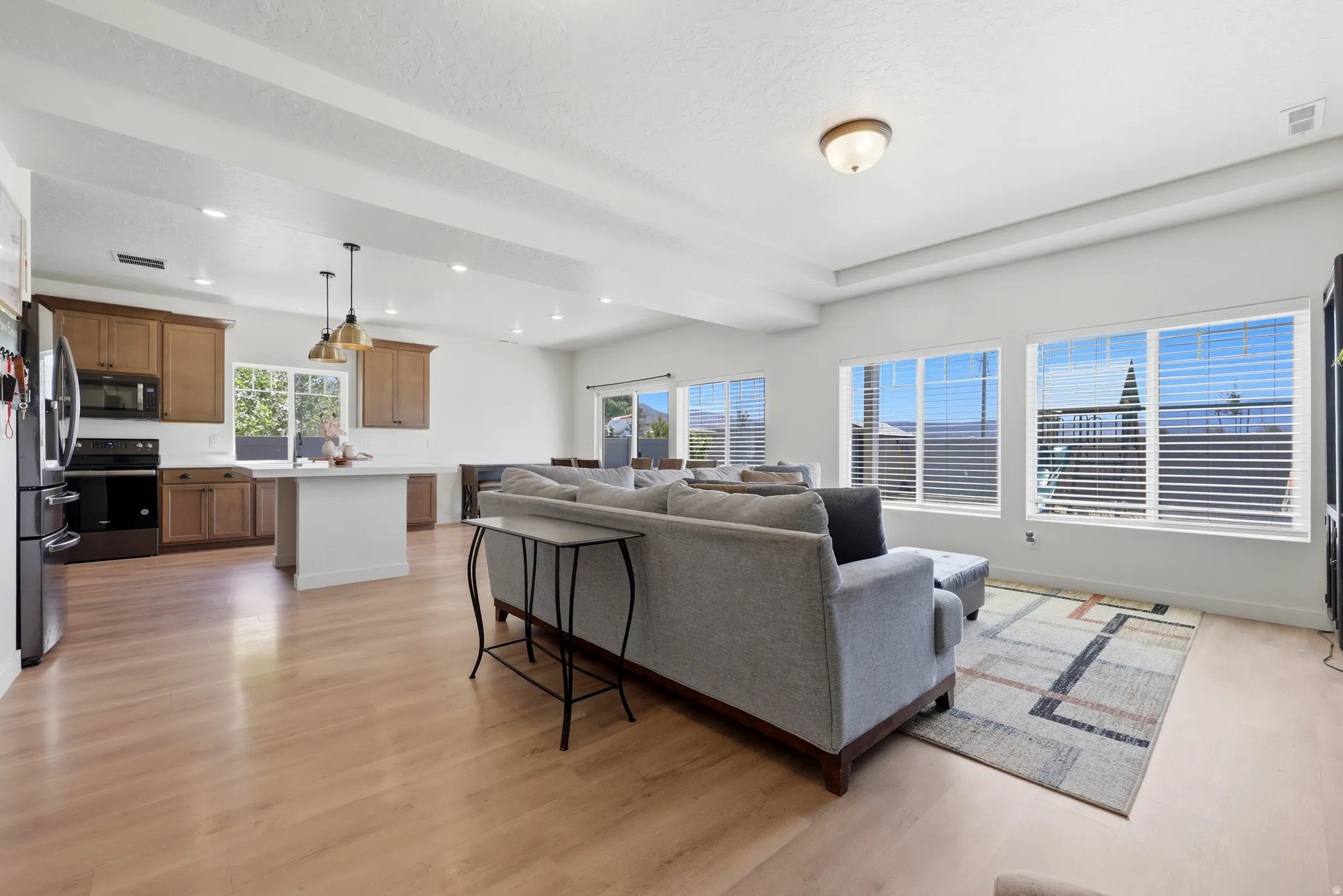 Open-concept living space featuring wood-finish flooring, recessed lighting, and multiple windows