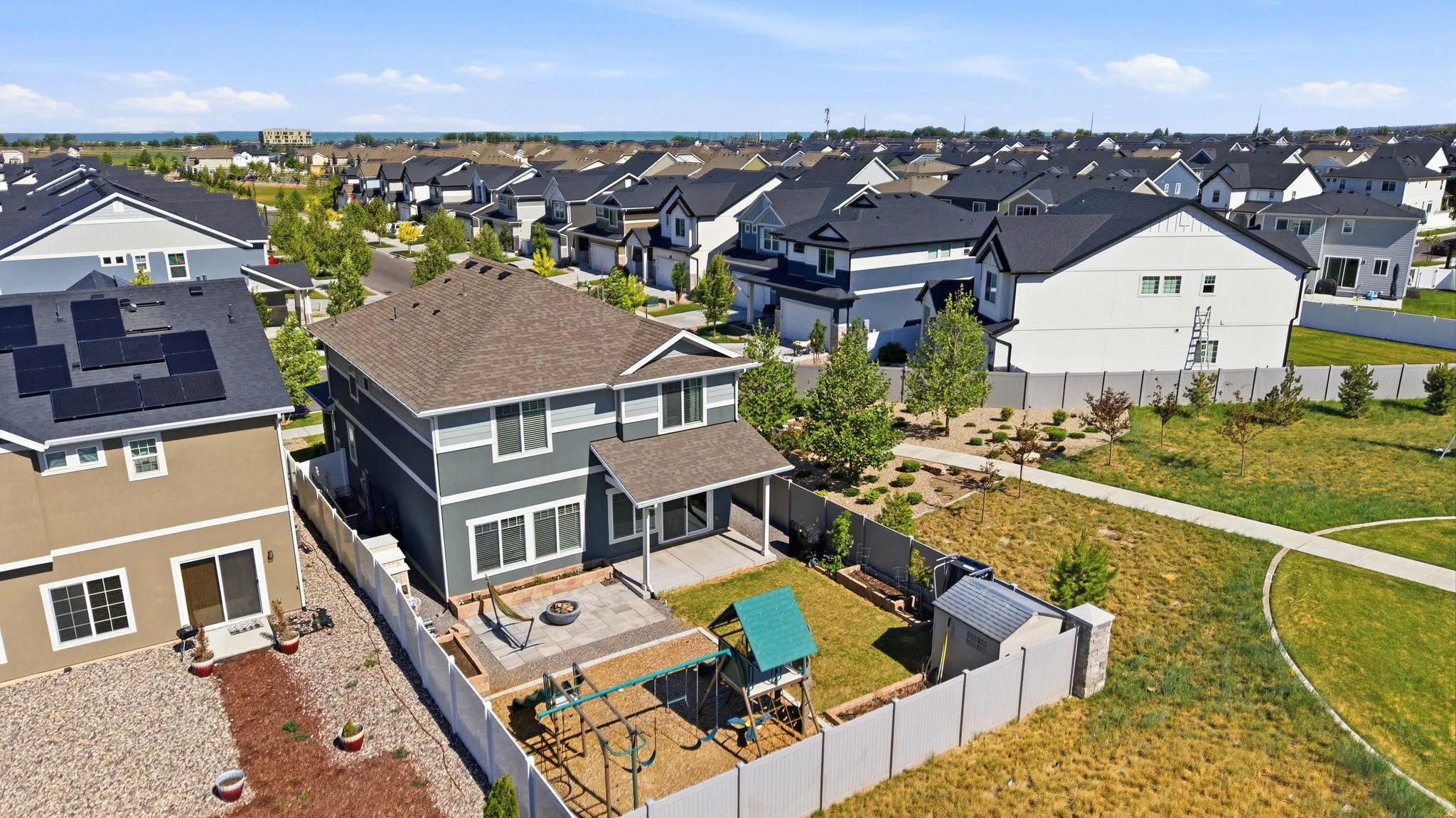 Contemporary two-story residence featuring a covered patio, paved outdoor area, and a private fenced yard with a storage shed