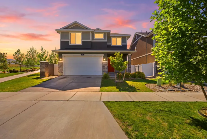 Modern two-story residence with a two-car garage, stone and siding exterior, red entry door, and concrete driveway