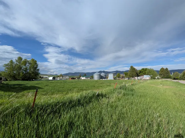 Expansive open field featuring green grass and a distant mountainous backdrop