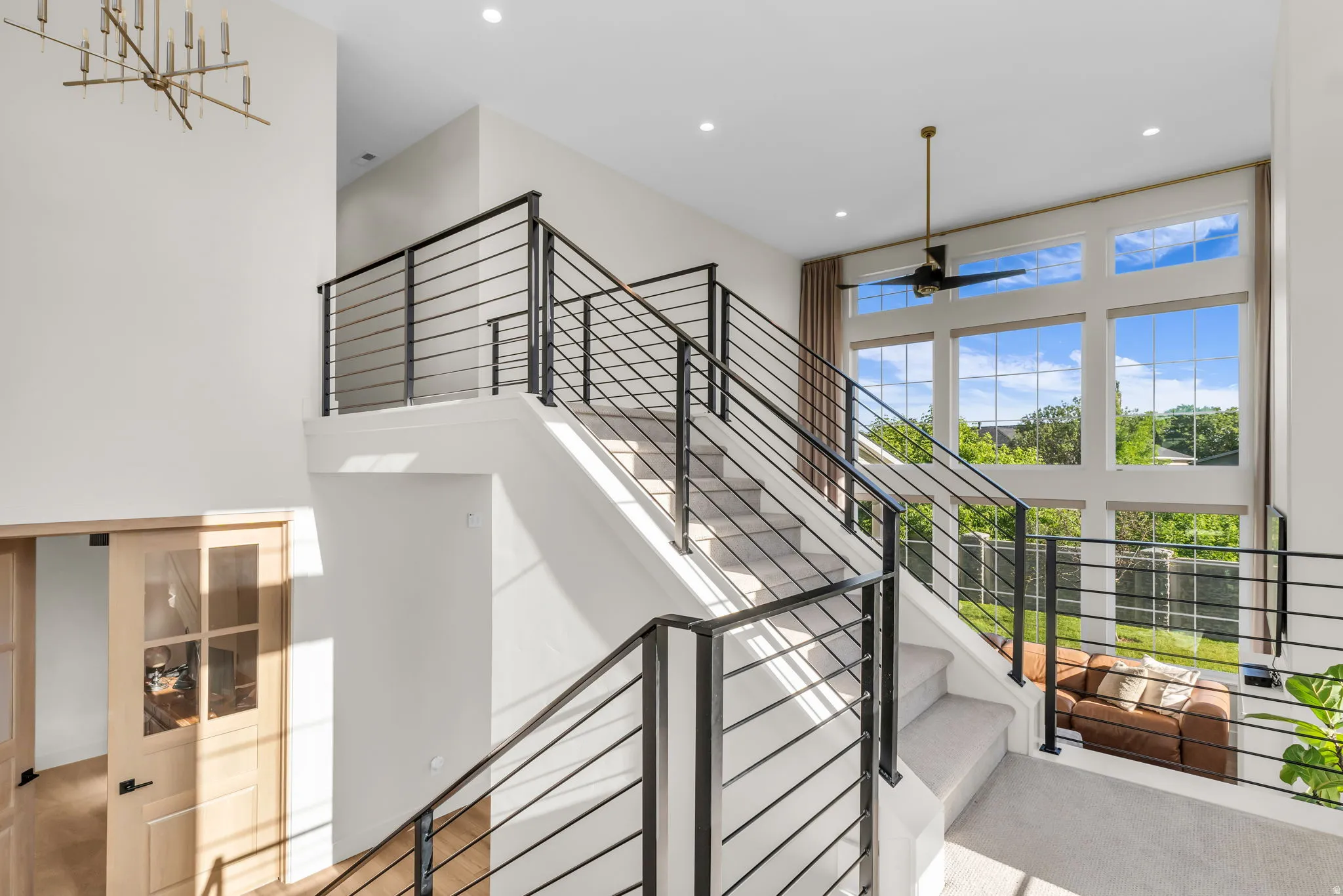 Multi-level interior featuring a contemporary staircase with black metal railings, soaring ceilings, and a dramatic wall of windows