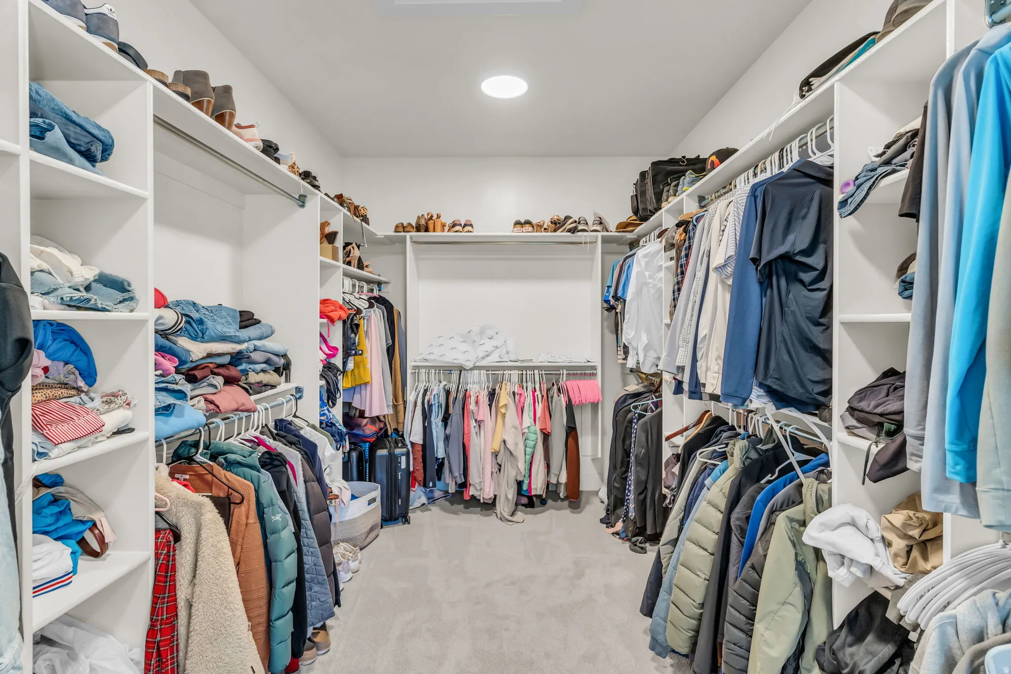 Walk-in closet featuring built-in shelving, multiple hanging rods, and recessed lighting
