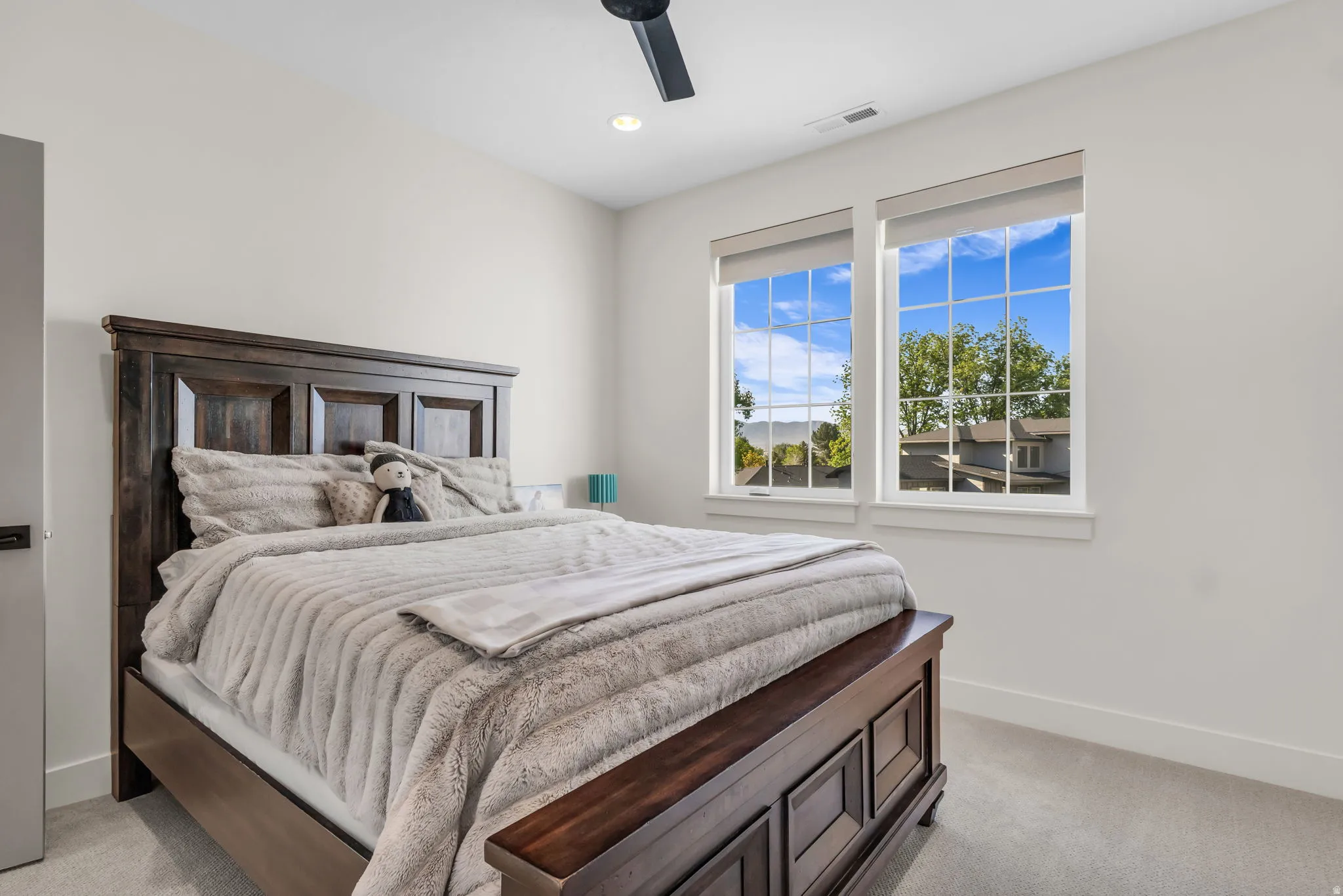 Bright room featuring two large windows with grid inserts, recessed lighting, a modern ceiling fan, and light-colored carpeting