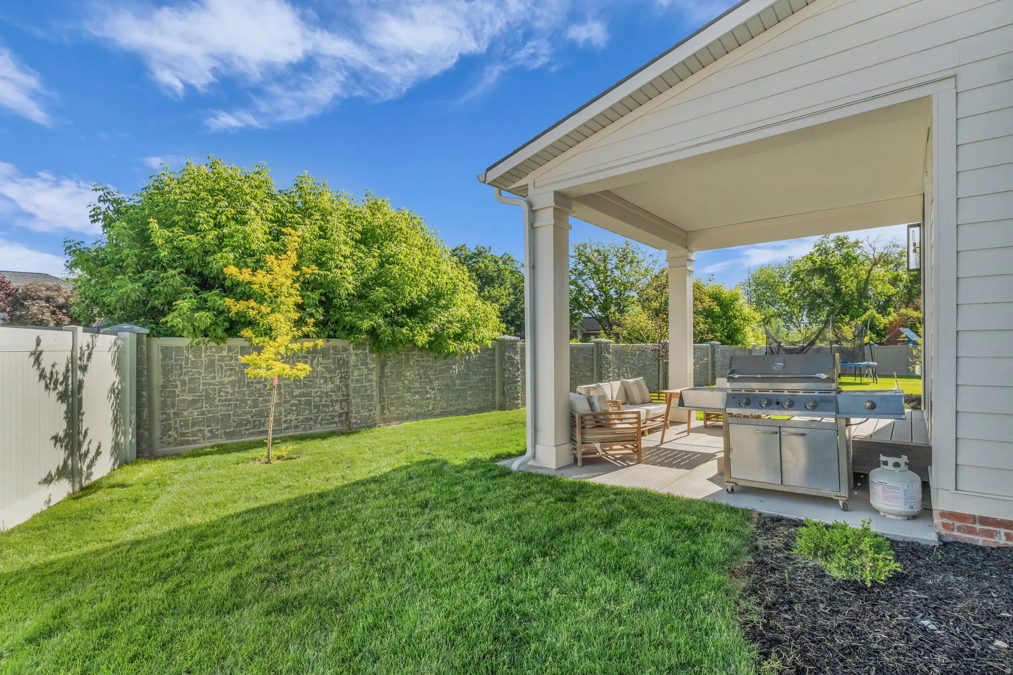 Covered patio with a concrete slab and columns, featuring a built-in outdoor grill