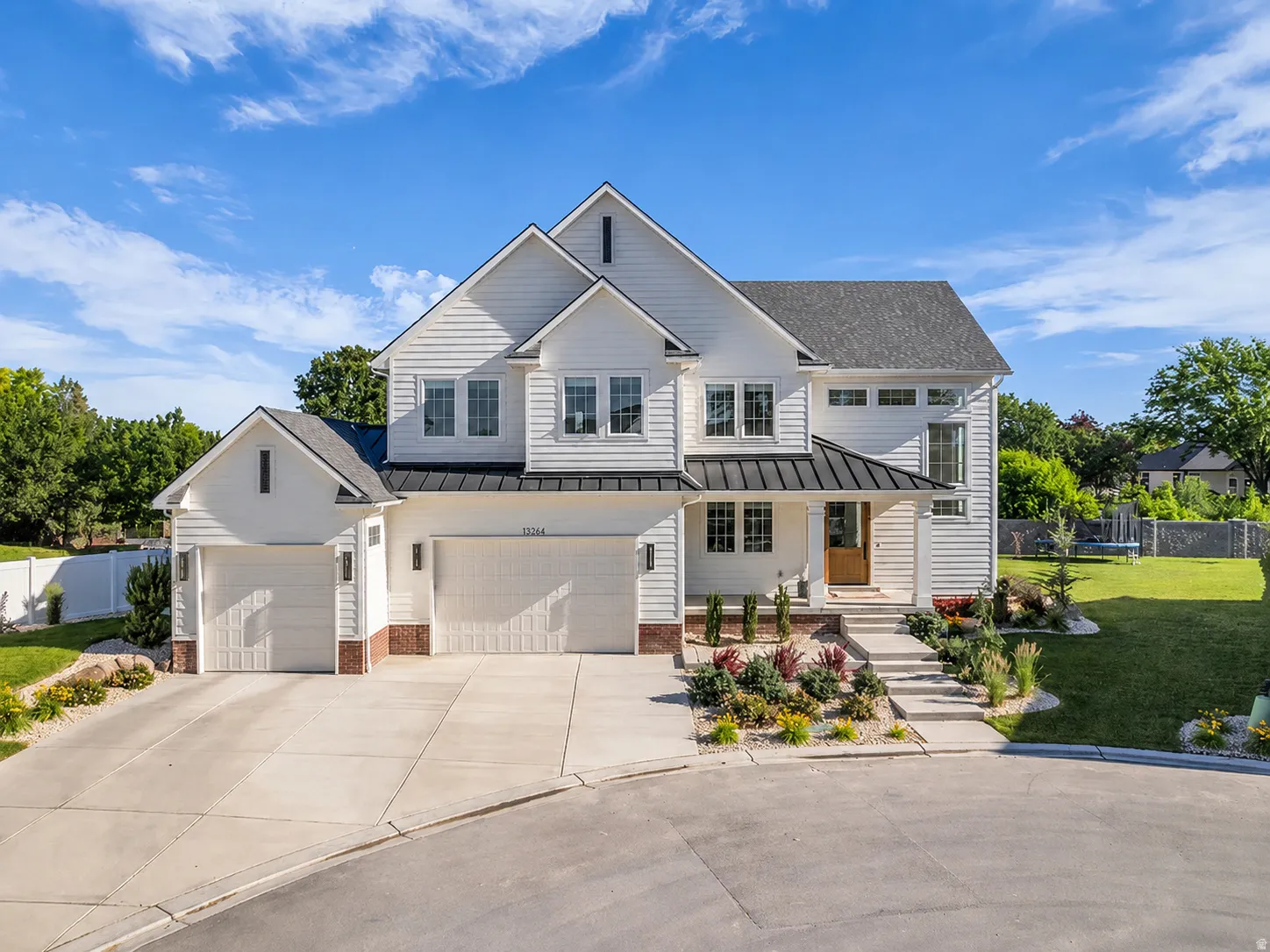 Modern farmhouse exterior featuring white horizontal siding, a dark asphalt shingle roof, and a prominent front entry with a wood door