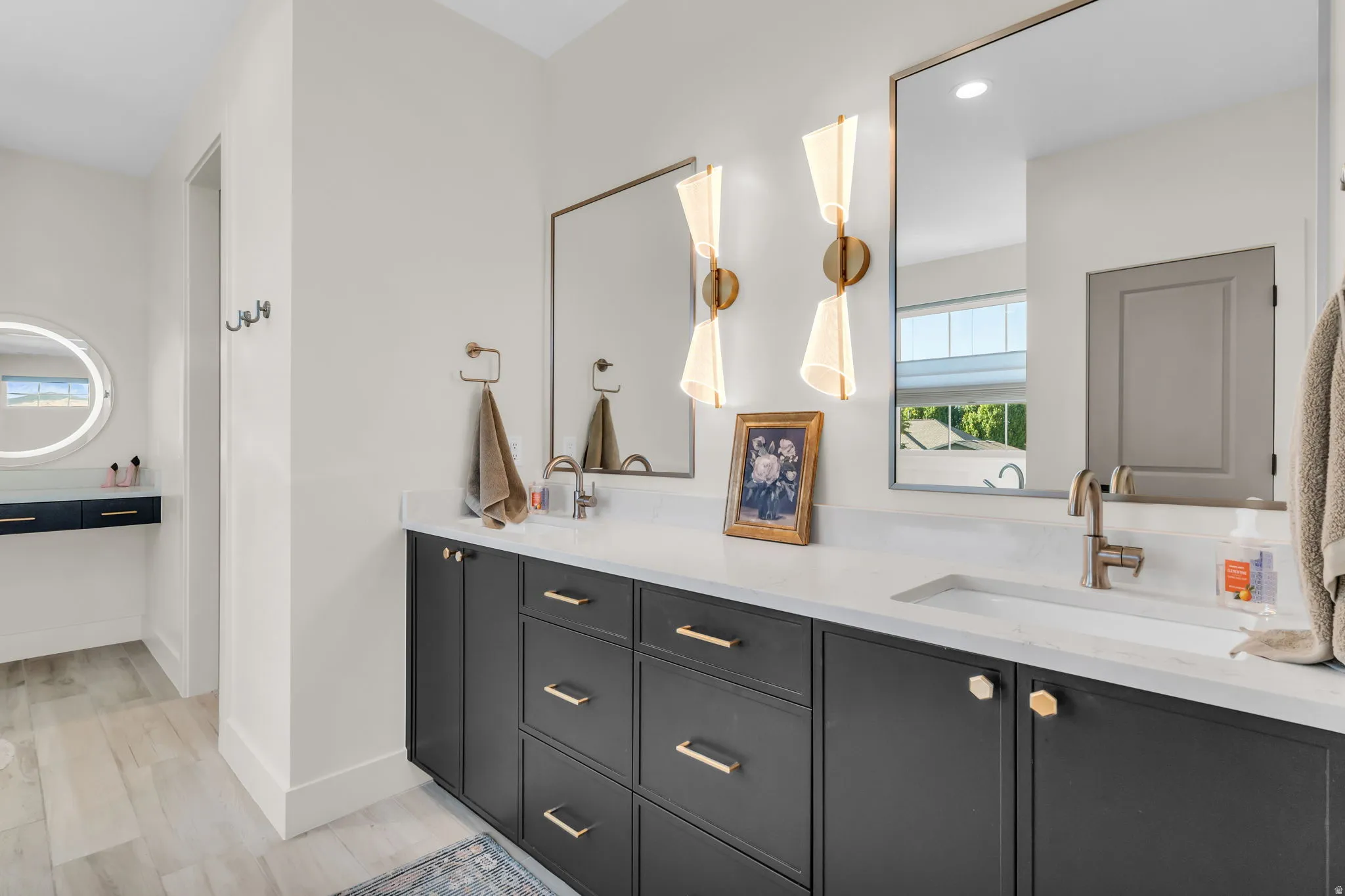 Dual vanity featuring black cabinetry with gold-finish hardware, integrated sinks, and quartz countertops