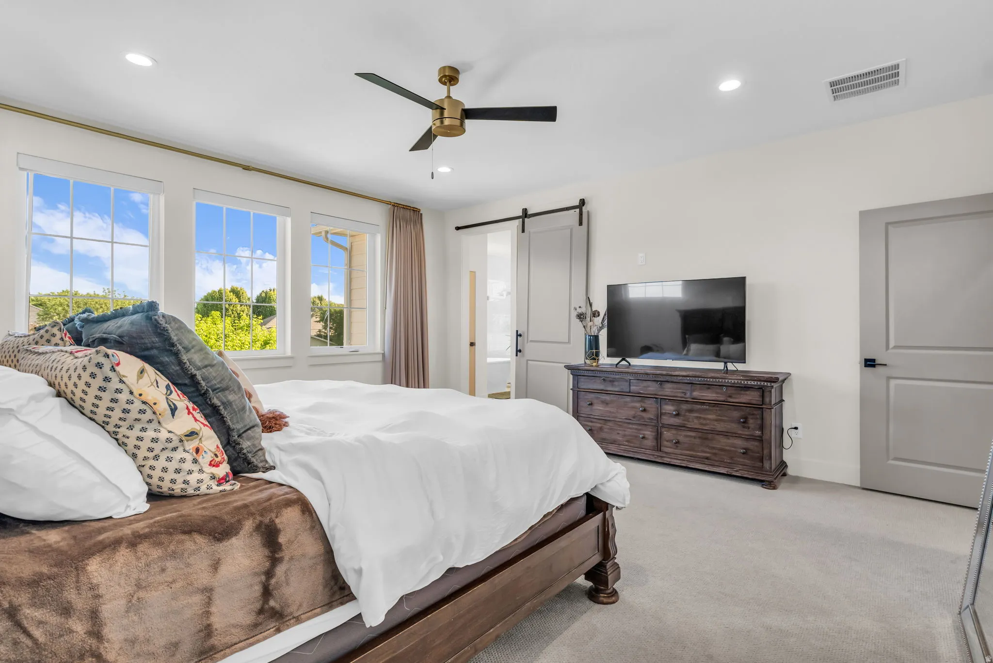 Light-filled interior featuring multiple windows with grid detailing, recessed lighting, and a ceiling fan