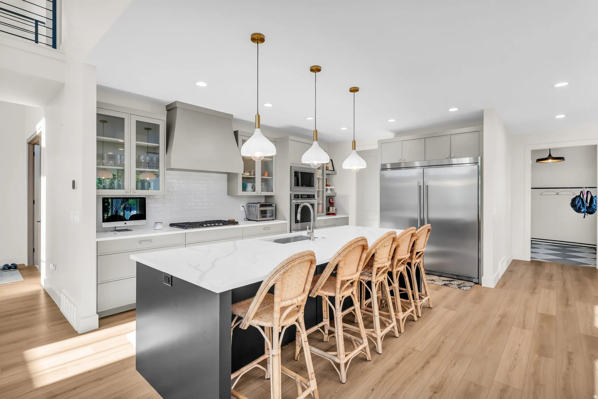 Spacious kitchen featuring a large island with seating, pendant lighting, professional-grade stainless steel appliances, light wood-finish flooring, and white subway tile backsplash