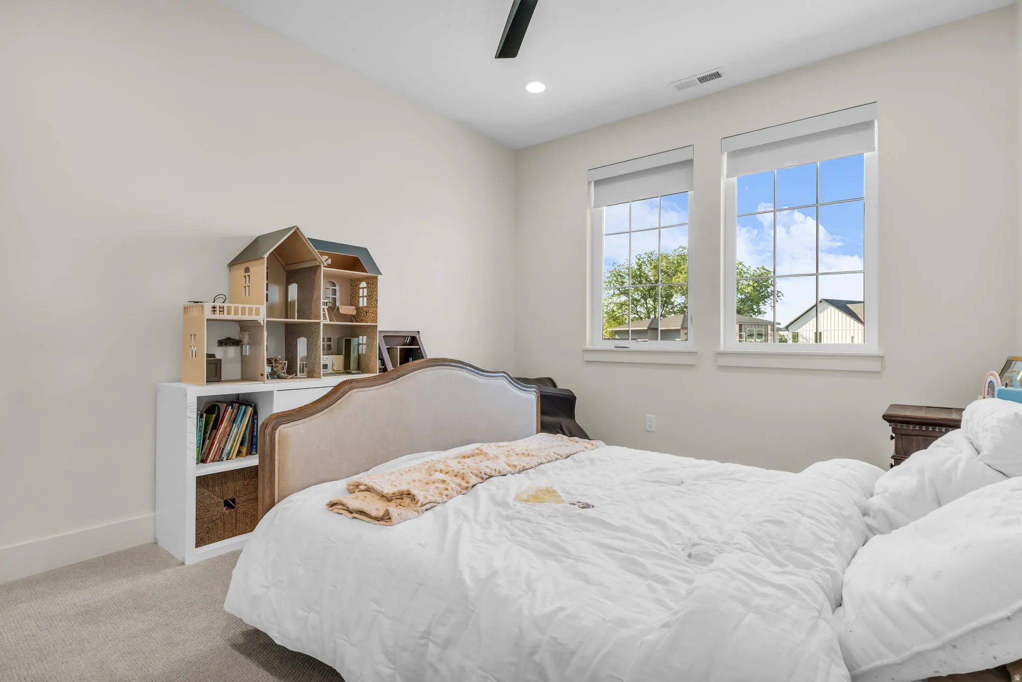 Carpeted room featuring dual windows with grids, an upholstered headboard, a ceiling fan, and recessed lighting
