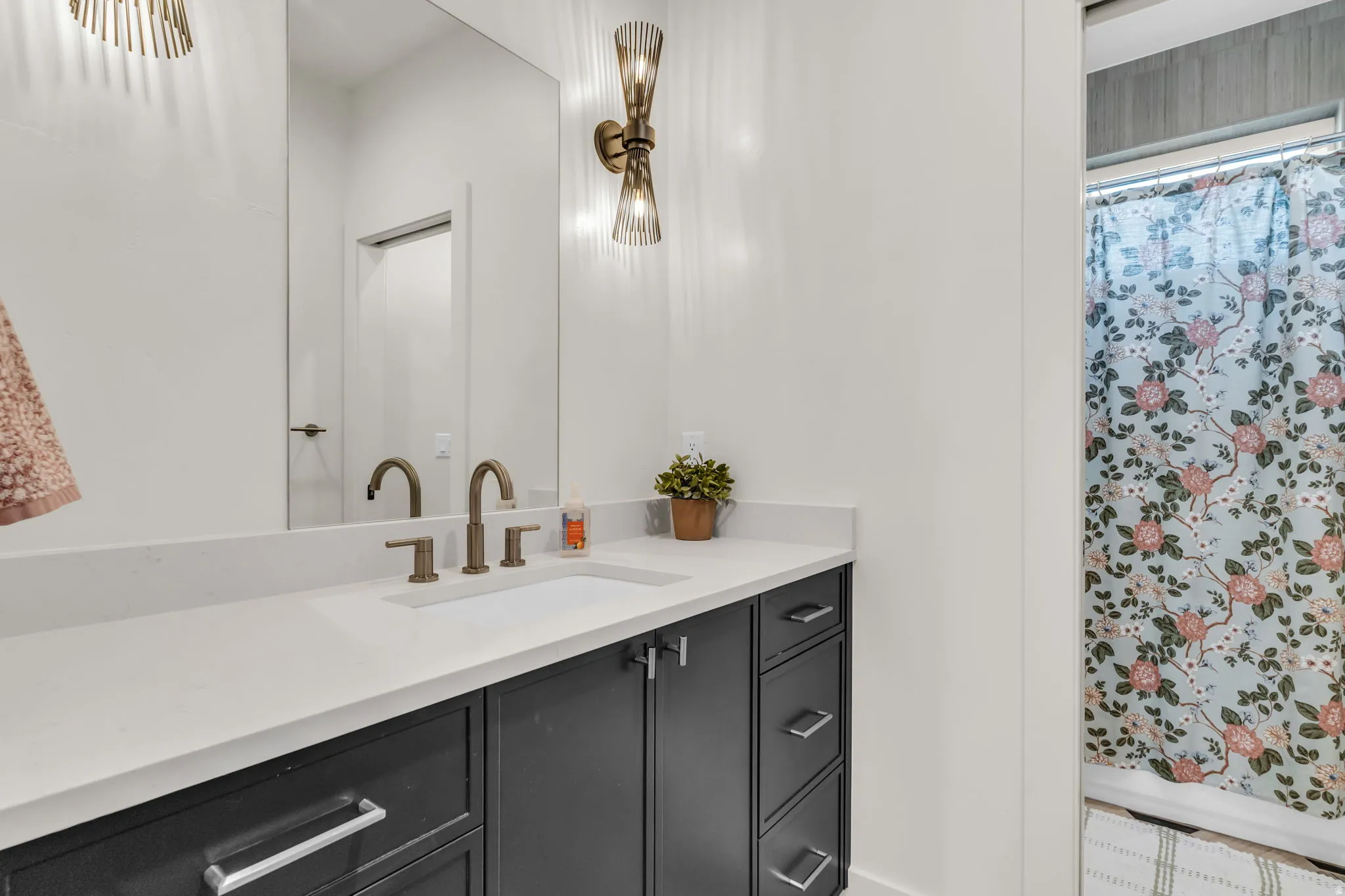 Bathroom vanity featuring a light-toned countertop with an integrated sink and brushed bronze-finish fixtures