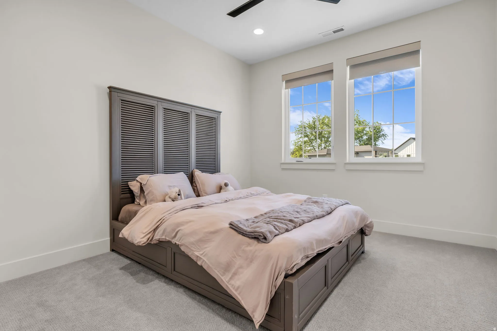 Bright interior space featuring two windows with roller shades, recessed lighting, and a ceiling fan
