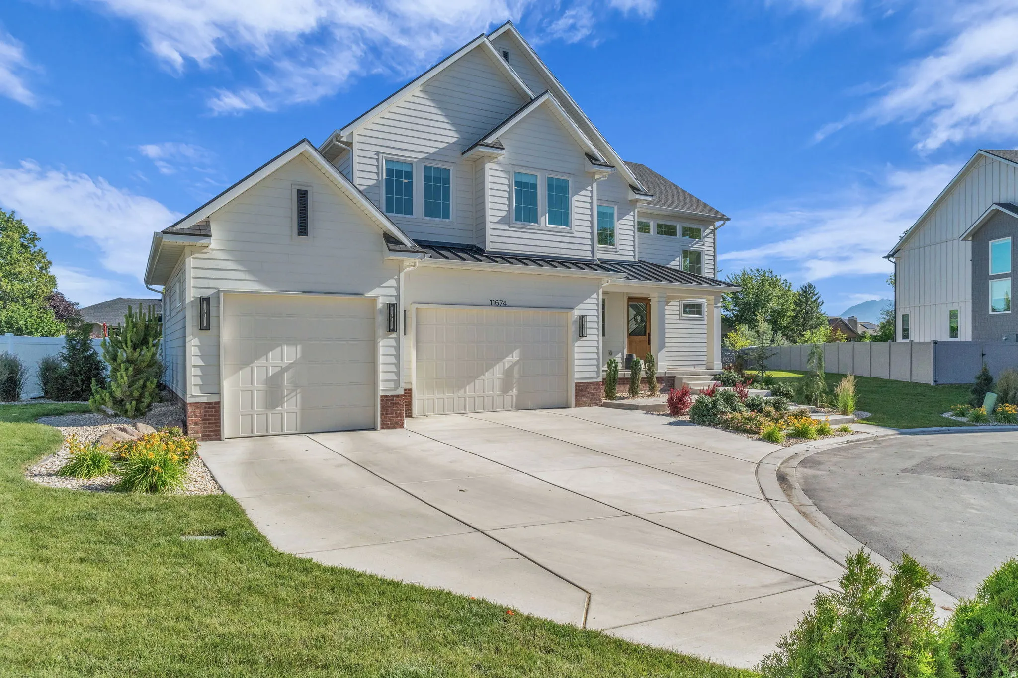 Contemporary residence featuring light-colored siding and a multi-car driveway