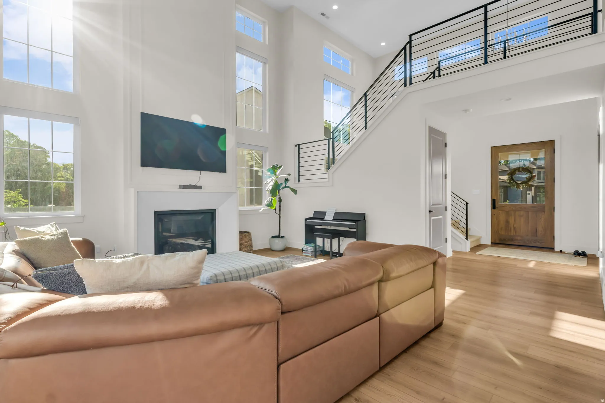 Living area featuring high ceilings, a fireplace with a white mantel, and wood-finish flooring