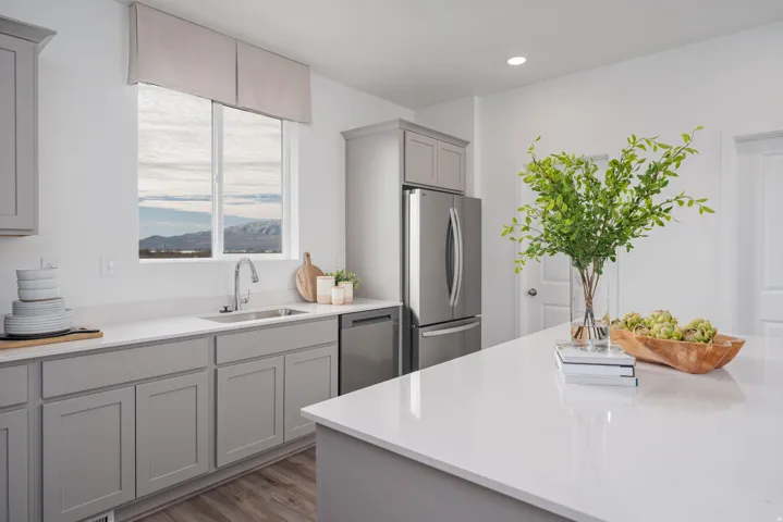 Modern kitchen featuring light gray cabinetry, stainless steel appliances, wood-finish flooring, and white countertops