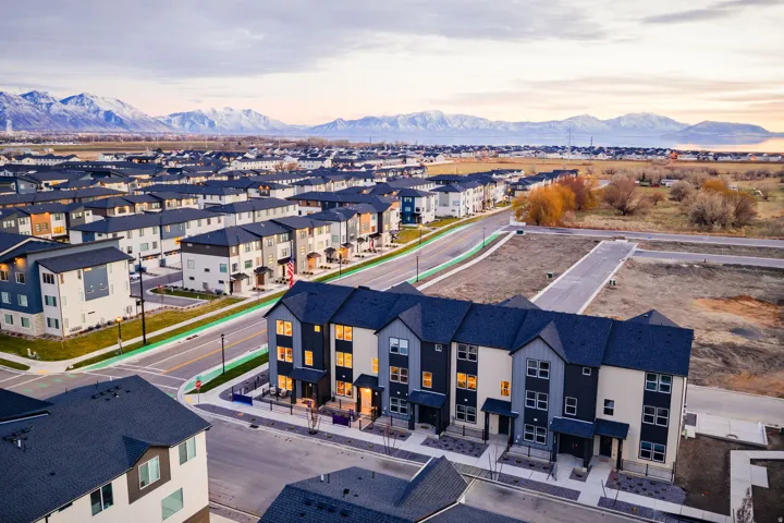 Modern townhomes with multi-tone facades and dark roofs, situated along paved streets