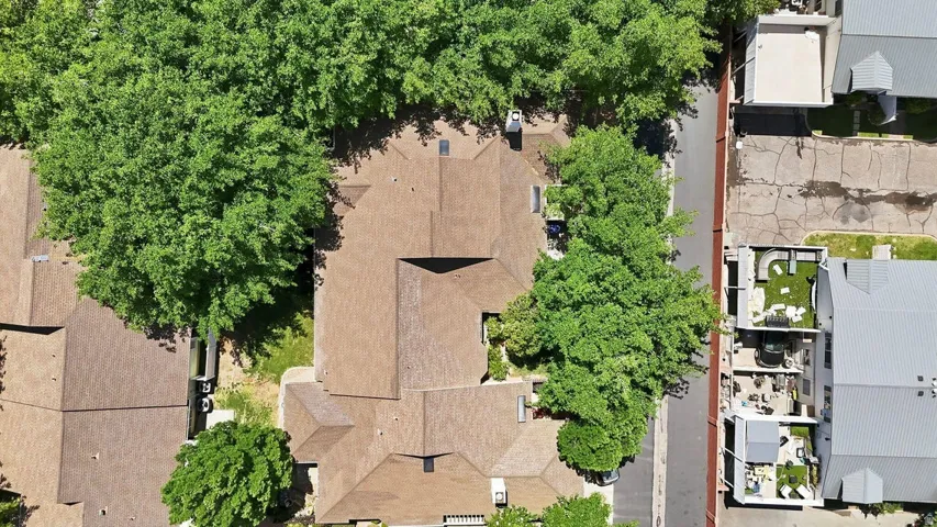 Multi-gabled roofline with brown shingles, surrounded by mature trees
