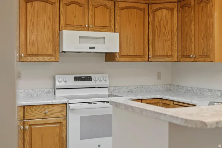 Kitchen featuring wood-finish cabinetry, white appliances, and a built-in microwave