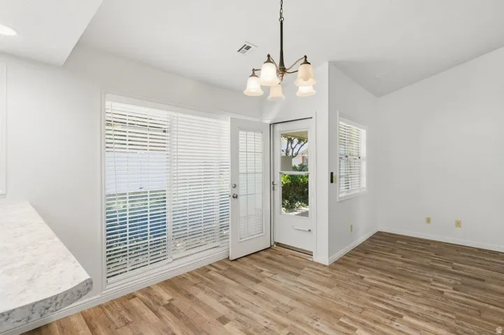 Dining area featuring wood-finish flooring, a contemporary chandelier, and a white countertop bar