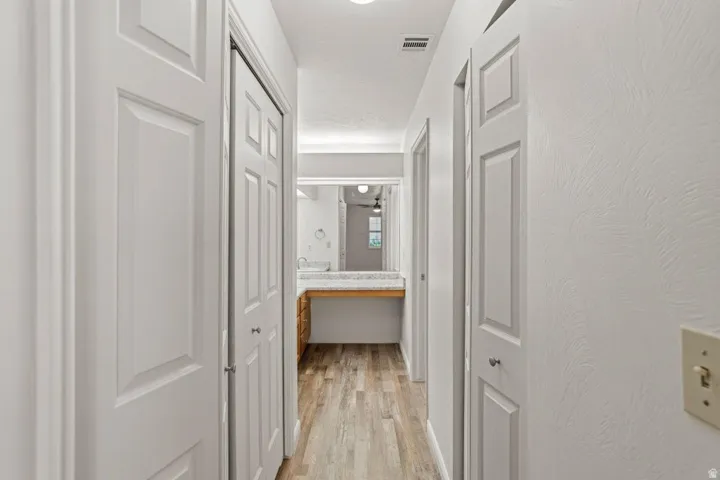 Hallway featuring wood-finish flooring, white panel doors, and textured walls