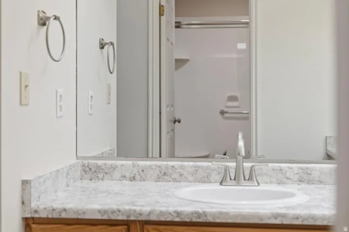 Bathroom vanity featuring a white oval sink, brushed nickel faucet, and a light-toned, speckled countertop