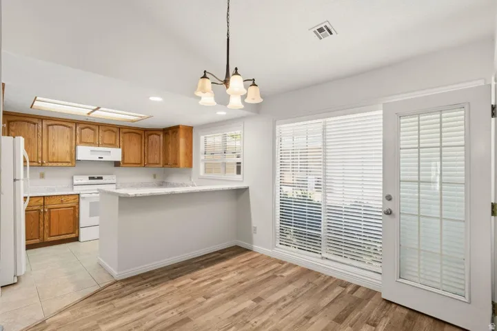 Kitchen and dining area featuring wood-finish flooring, a breakfast bar, white countertops, and a sliding glass door with an adjacent full-lite exterior door