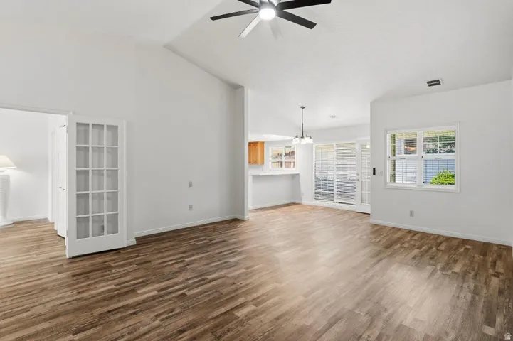 Spacious living area featuring wood-finish flooring, vaulted ceilings, and a ceiling fan