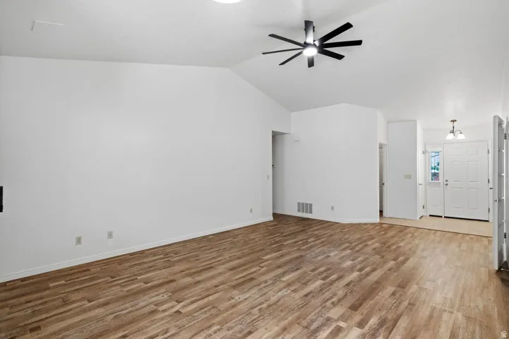Spacious interior featuring wood-finish flooring, vaulted ceiling, and a modern ceiling fan
