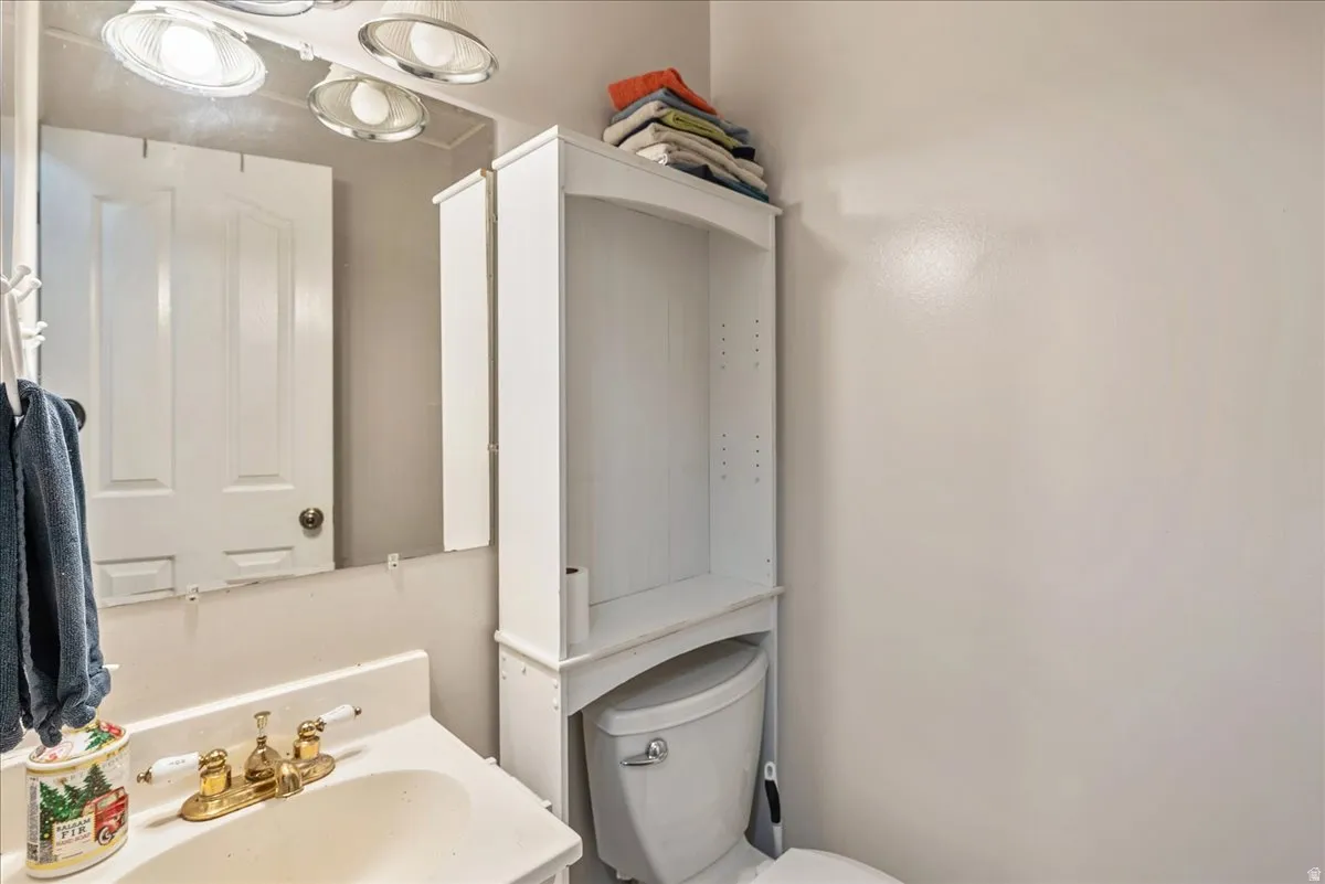 Bathroom featuring a white vanity with an integrated sink, polished brass-finish faucet, and a wall-mounted mirror with overhead lighting